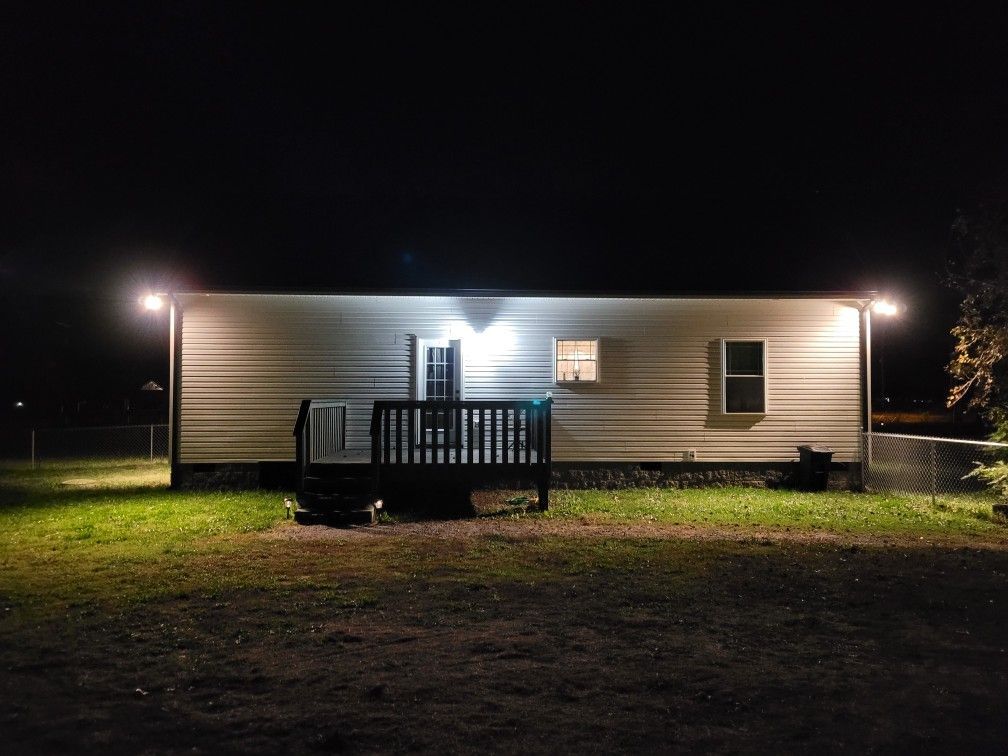 A white house with a deck is lit up at night.
