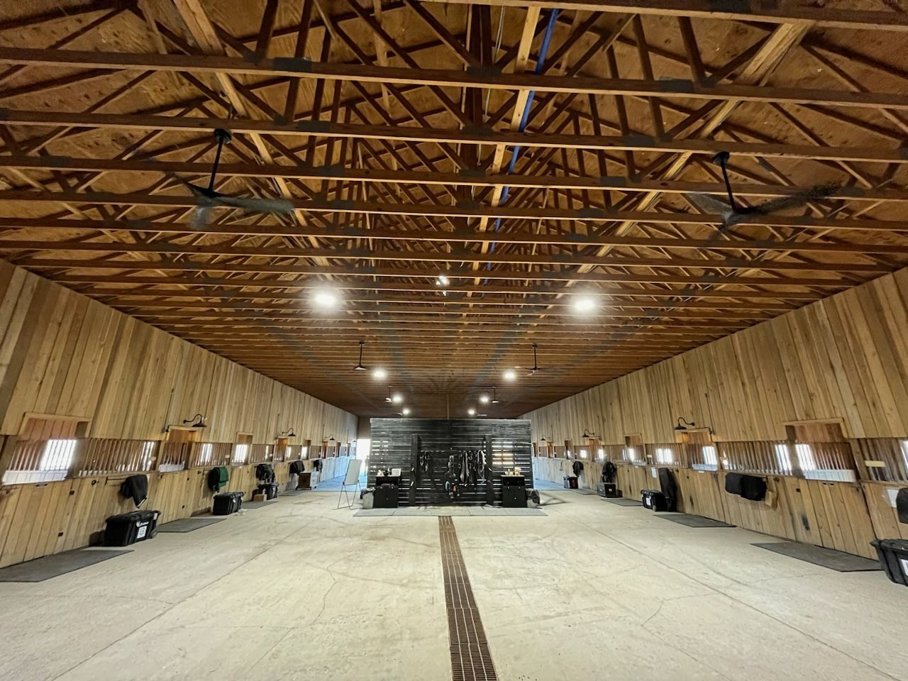 A large wooden barn with a lot of horses in it.