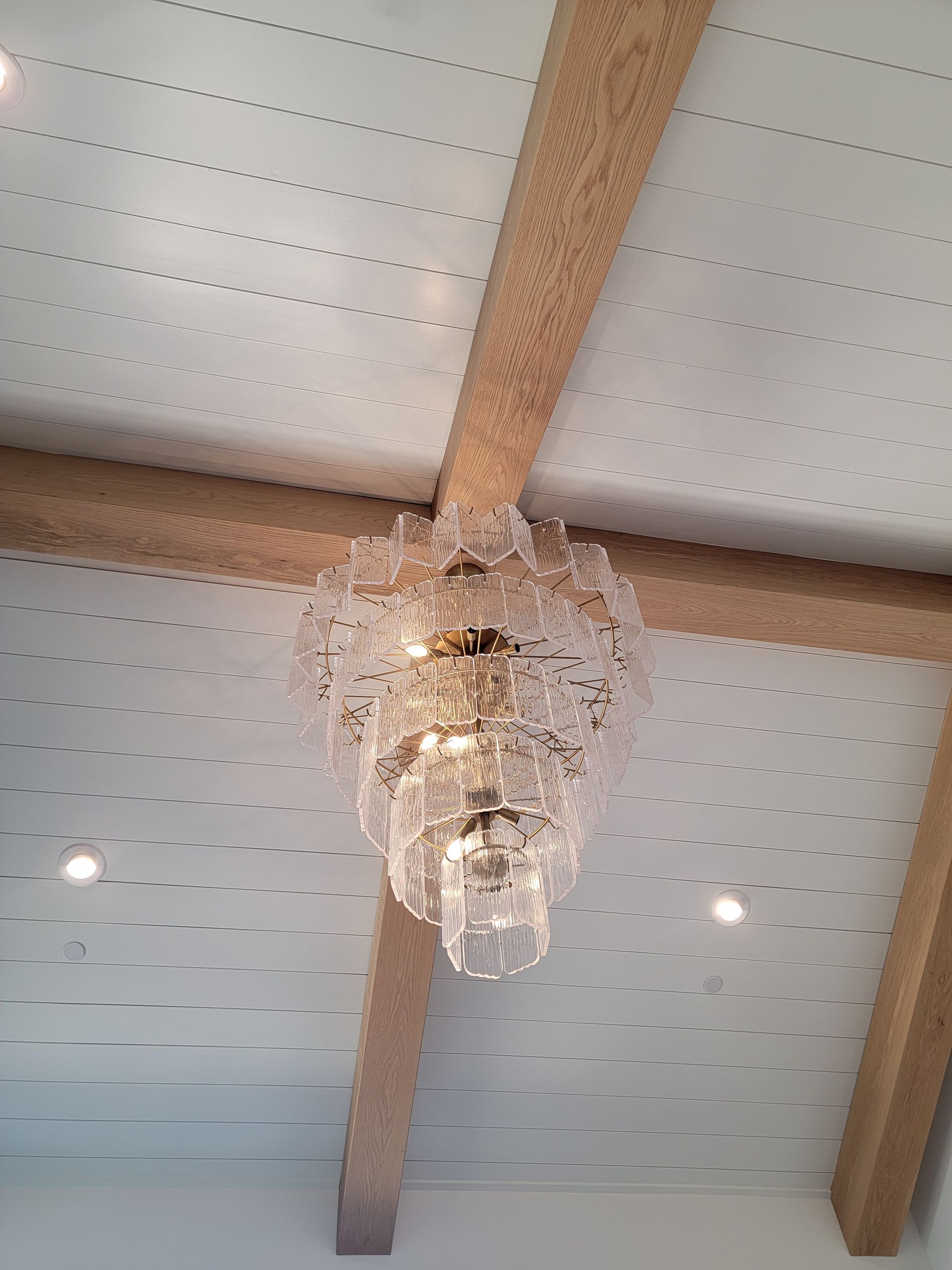 Crystal chandelier hanging from a white ceiling with wooden beams.