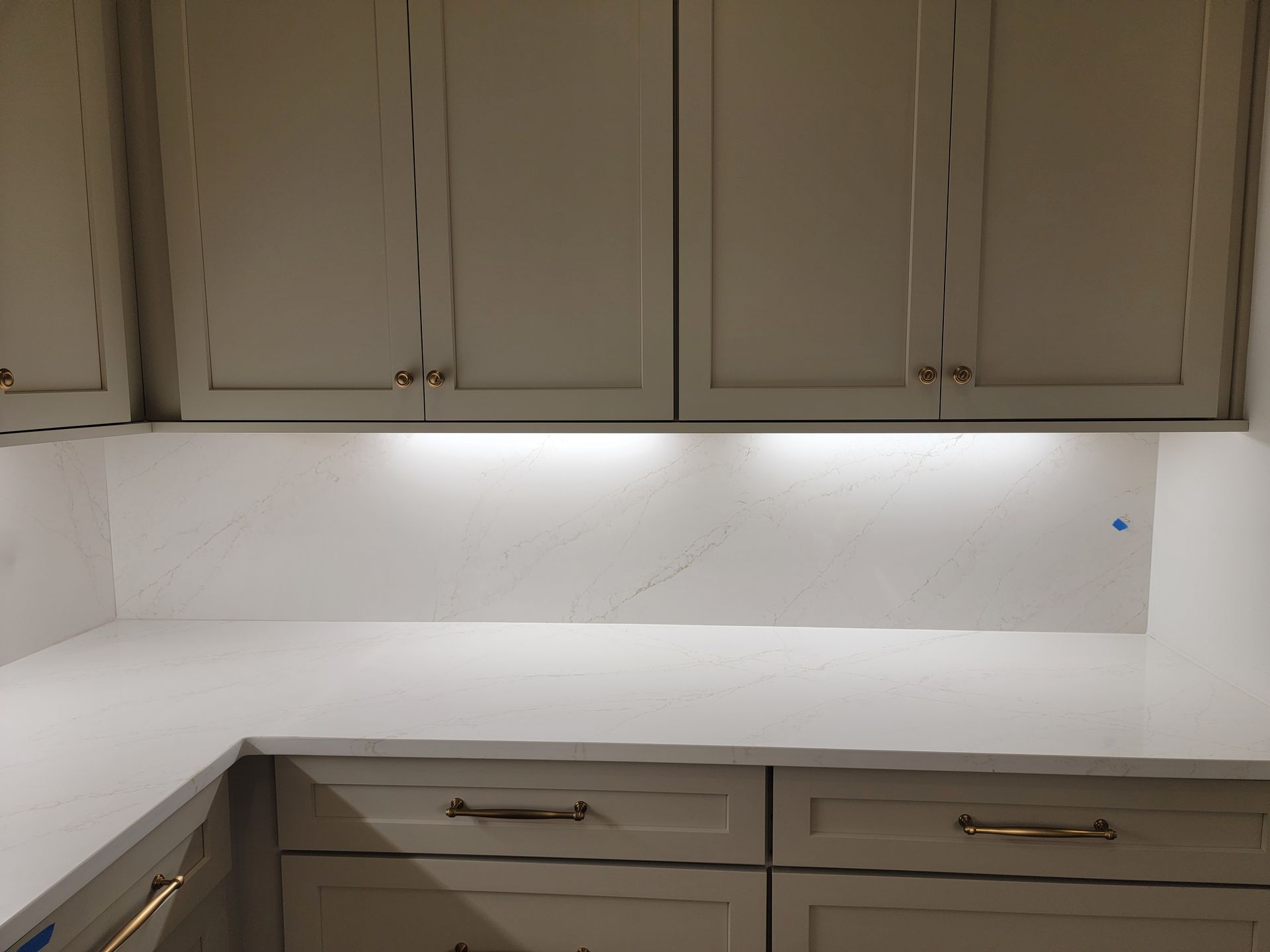 Kitchen cabinets in light gray with white countertops and under-cabinet lighting.