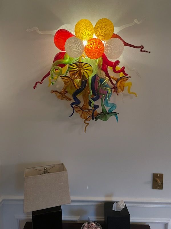 A lamp is sitting on a table next to a wall with balloons on it.