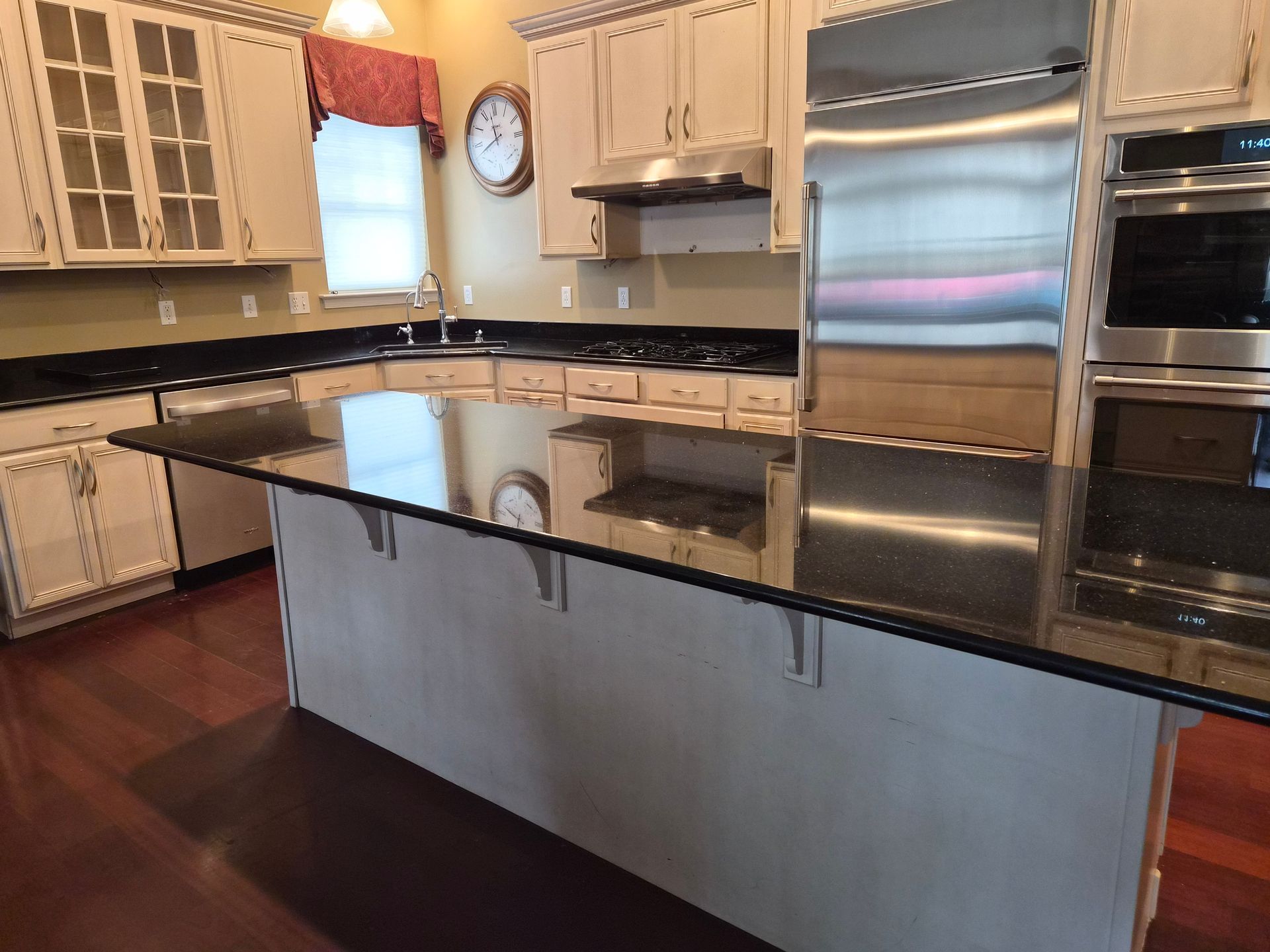 Kitchen with black countertops, light cabinets, stainless steel appliances, and a central island.