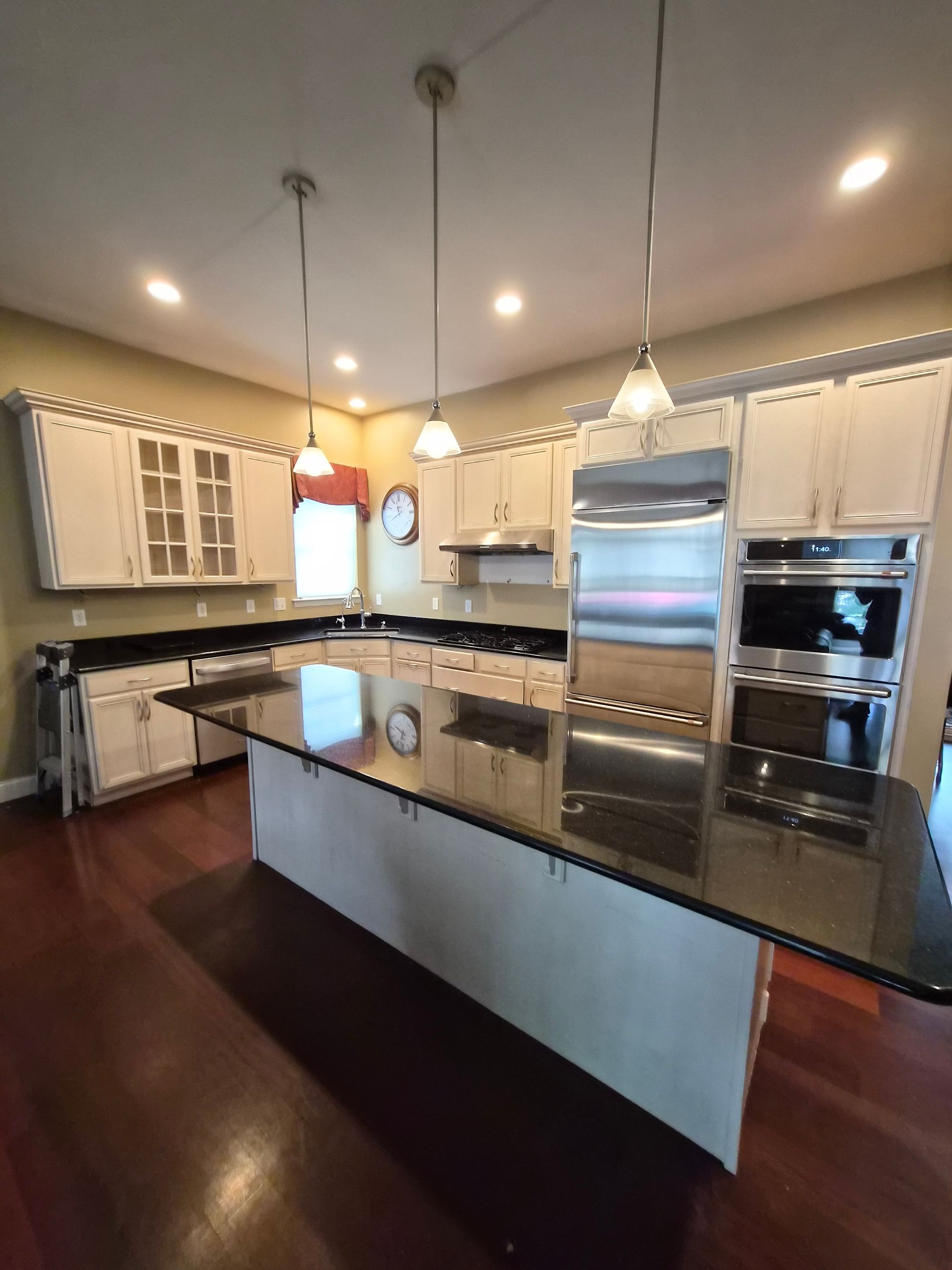 Kitchen with large island, stainless steel appliances, white cabinets, and dark countertops.