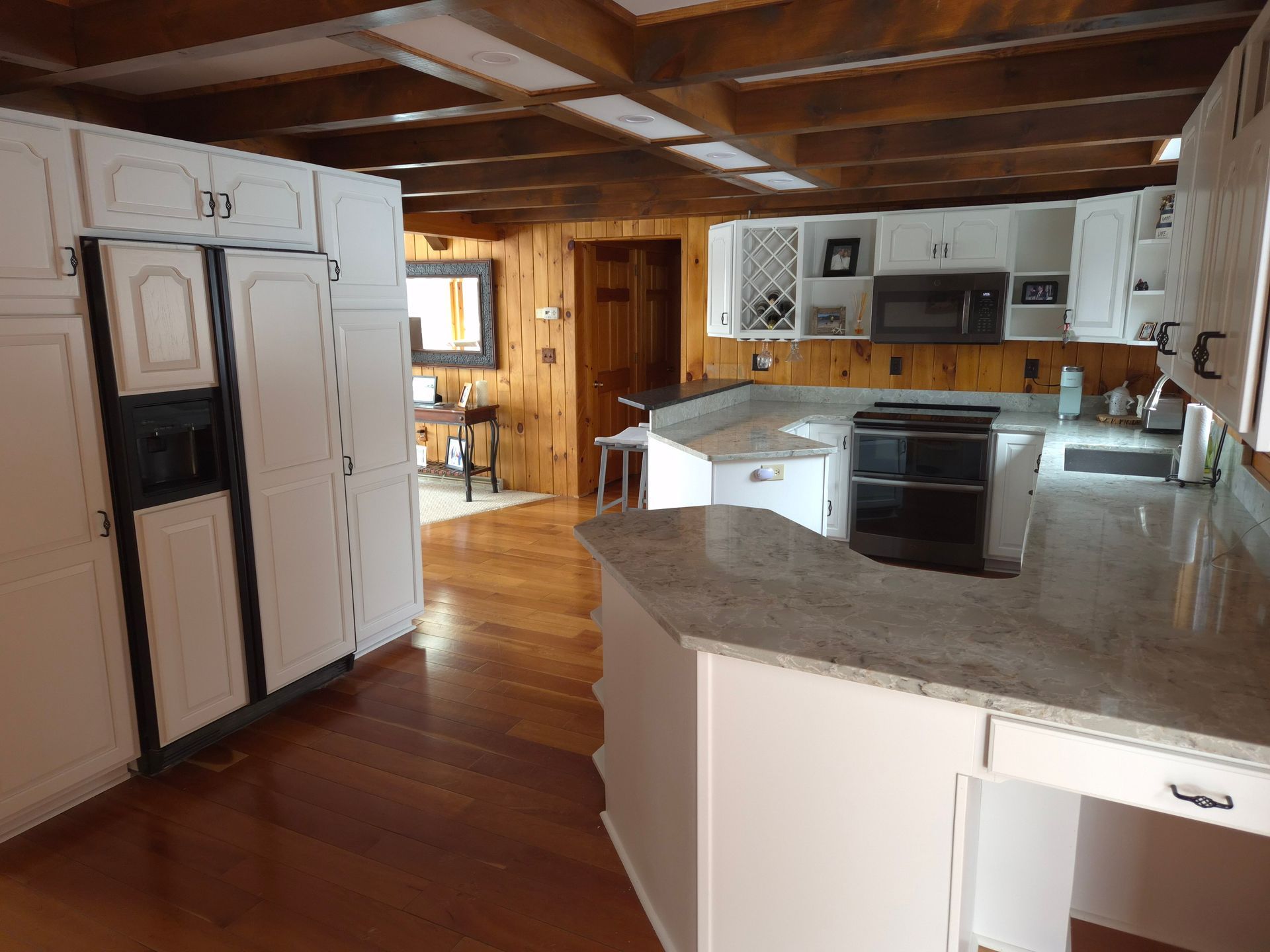 Kitchen with white cabinets, wood floors, and granite countertops.