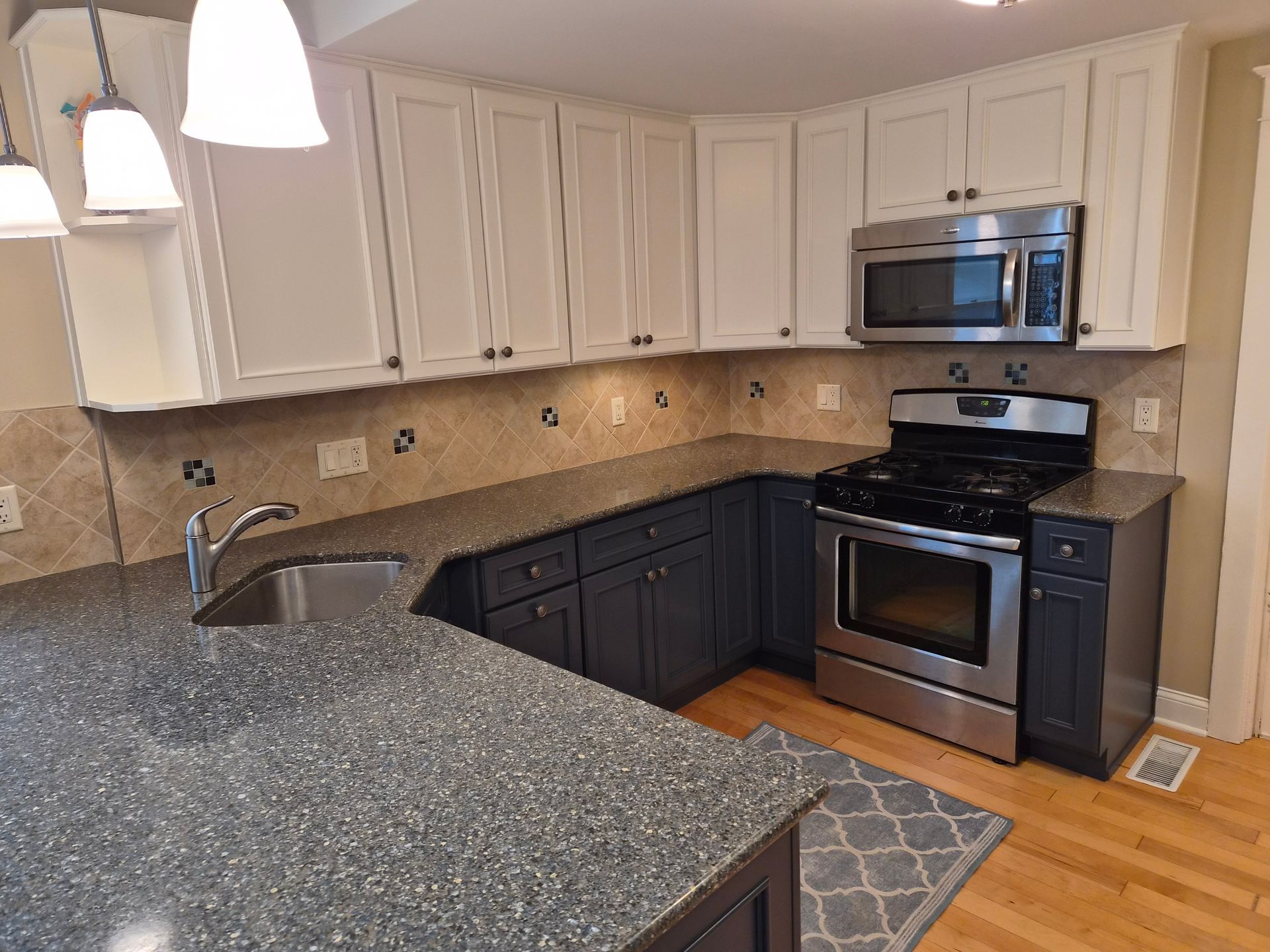 Kitchen with white upper cabinets, dark blue lower cabinets, and stainless steel appliances.