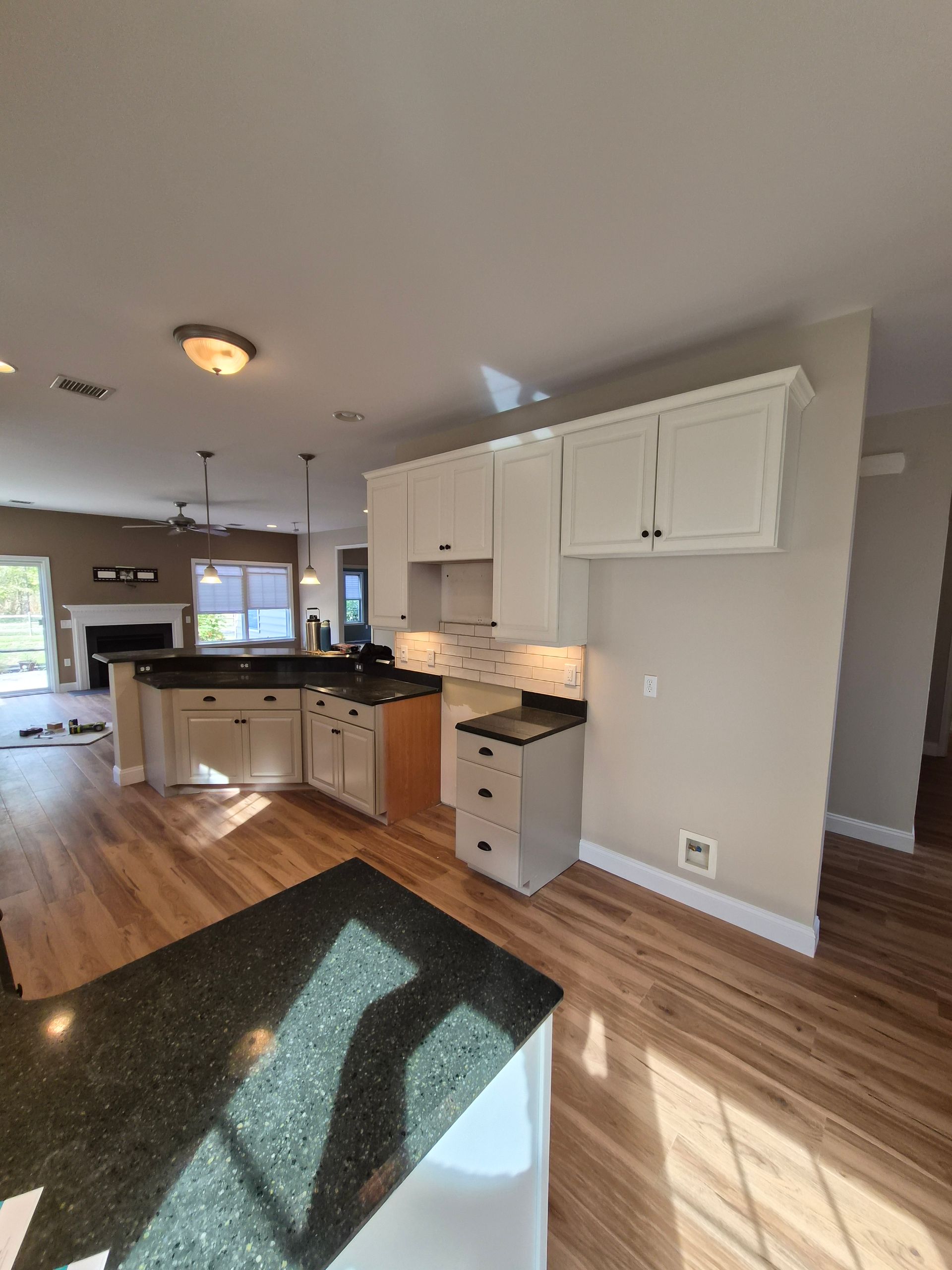 Kitchen with light wood floors, white cabinets, and dark granite countertops.