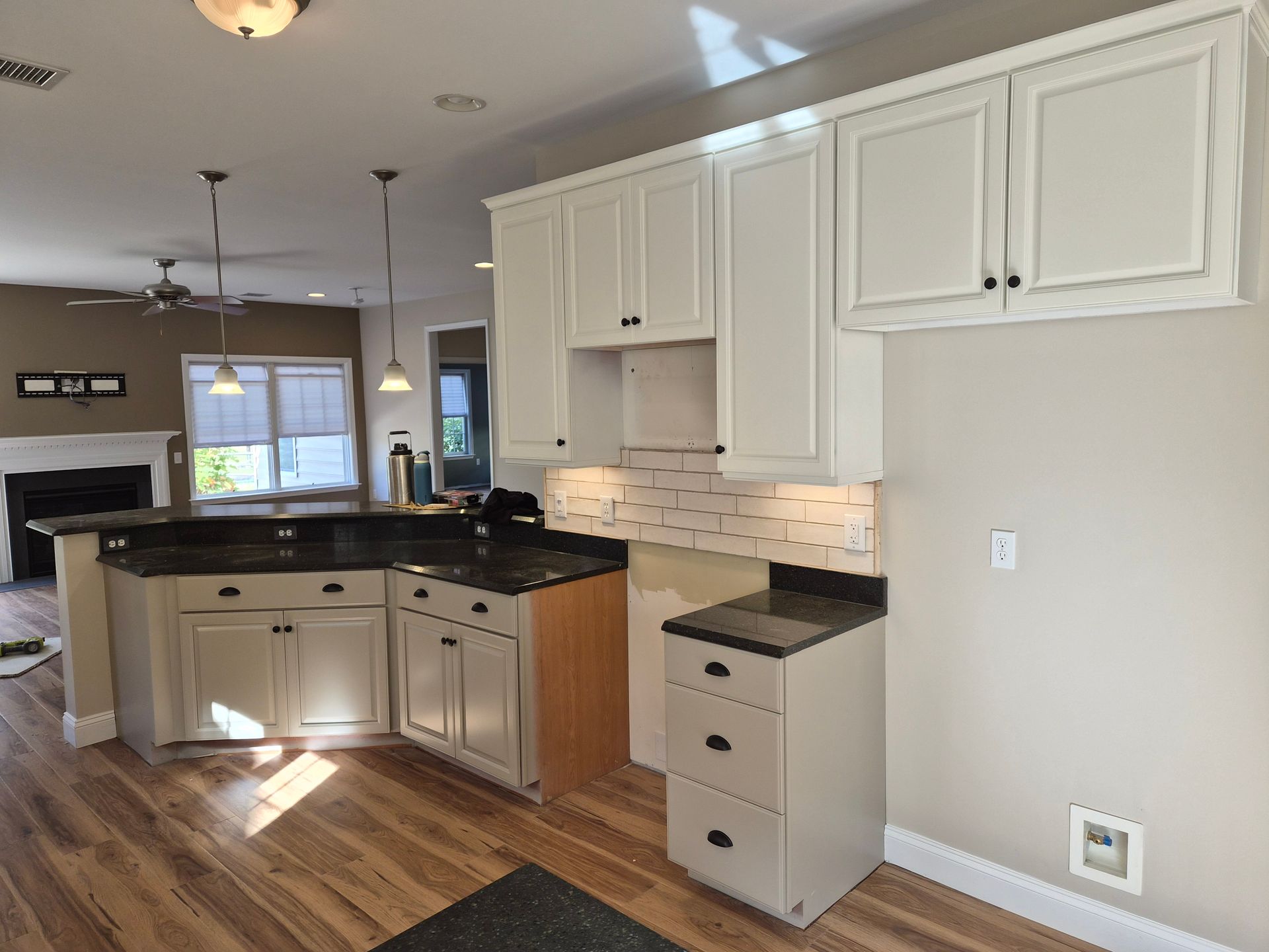 Kitchen with white cabinets, dark countertop, and wooden floor.