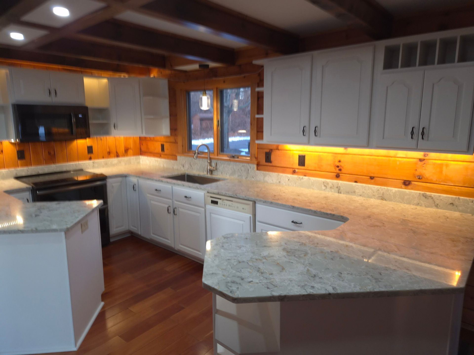 White kitchen with granite countertops, wood accents, and built-in appliances.