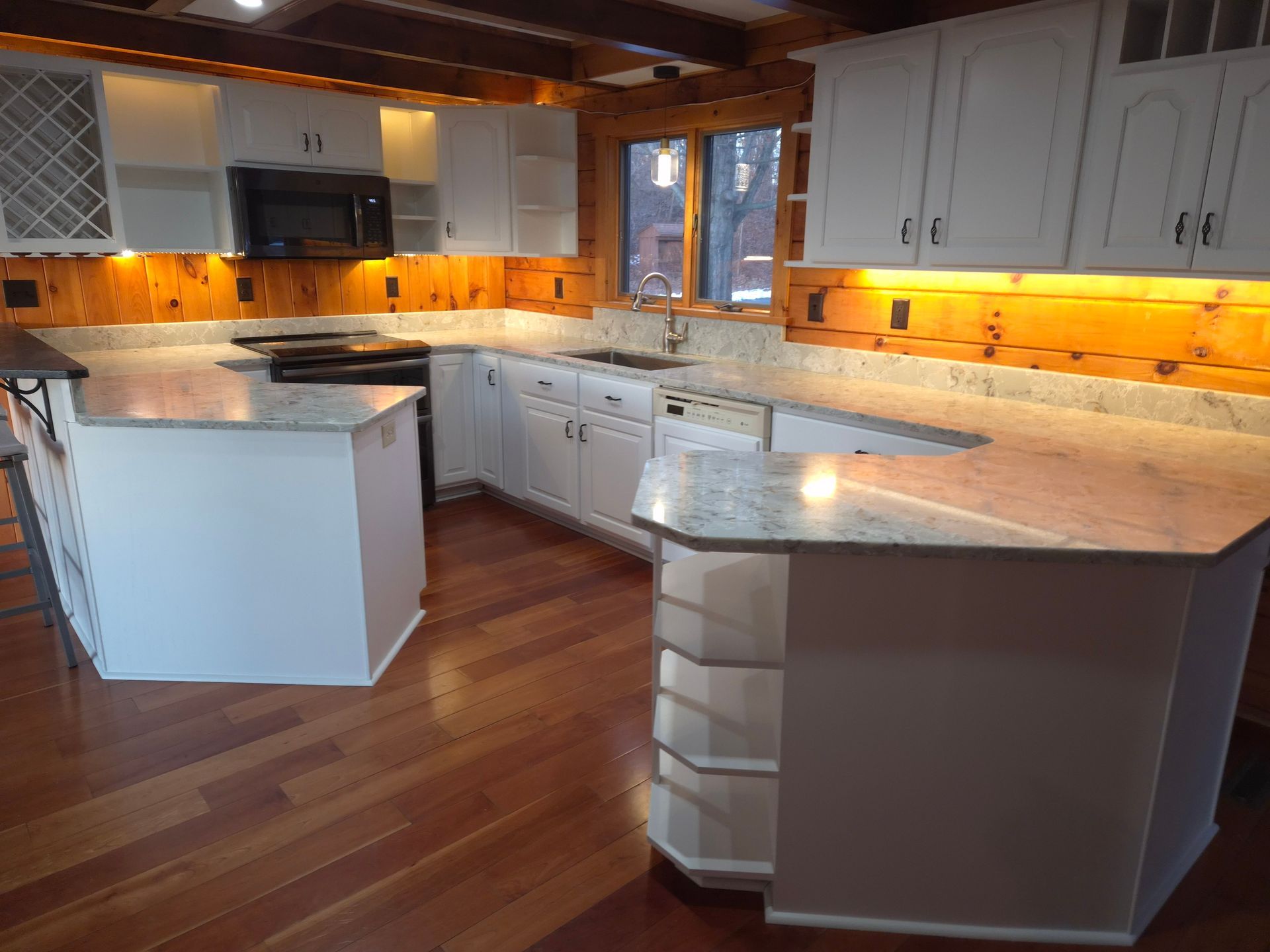 Kitchen with white cabinets, granite countertops, and wood floors.