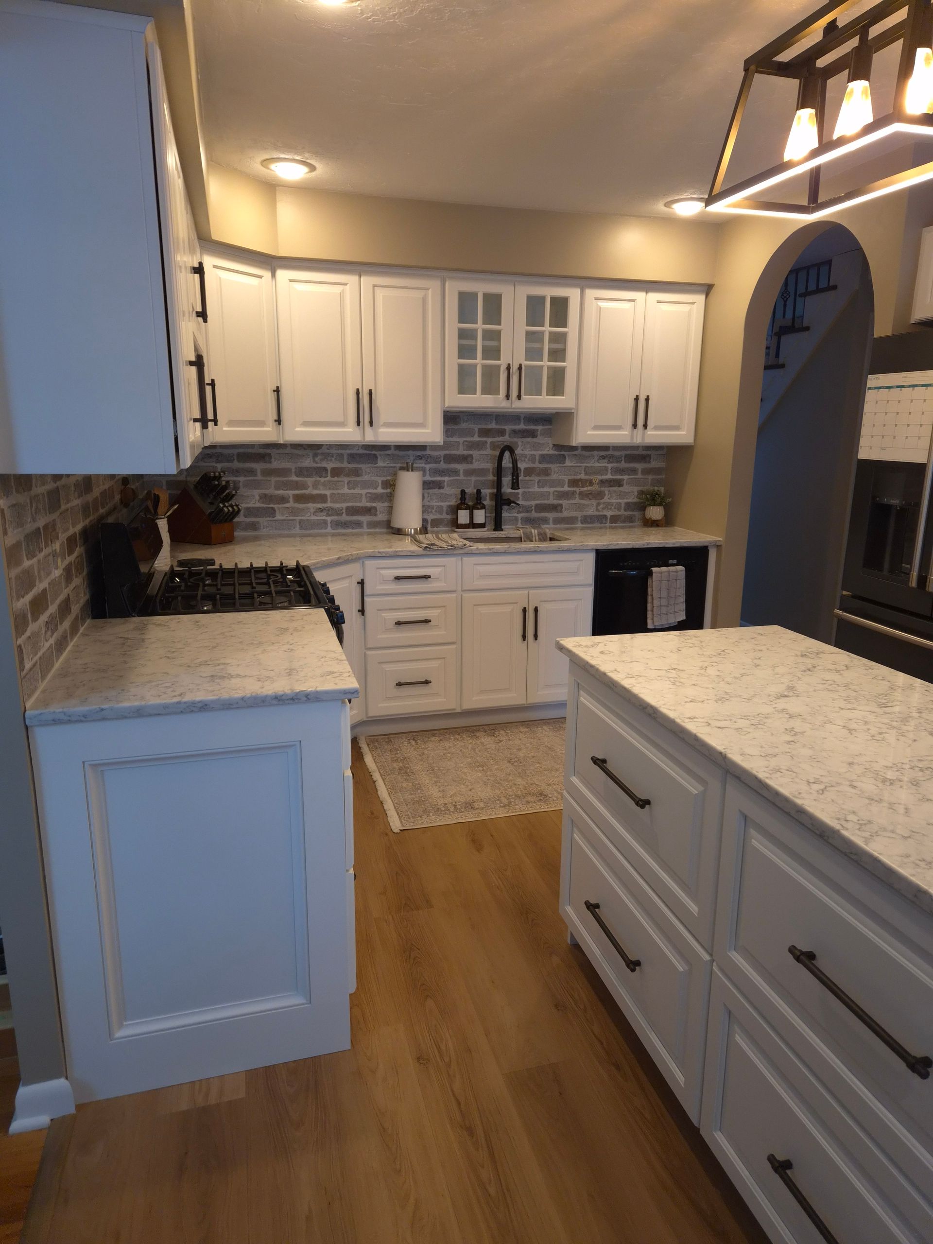 White kitchen with granite countertops, brick backsplash, and a center island.