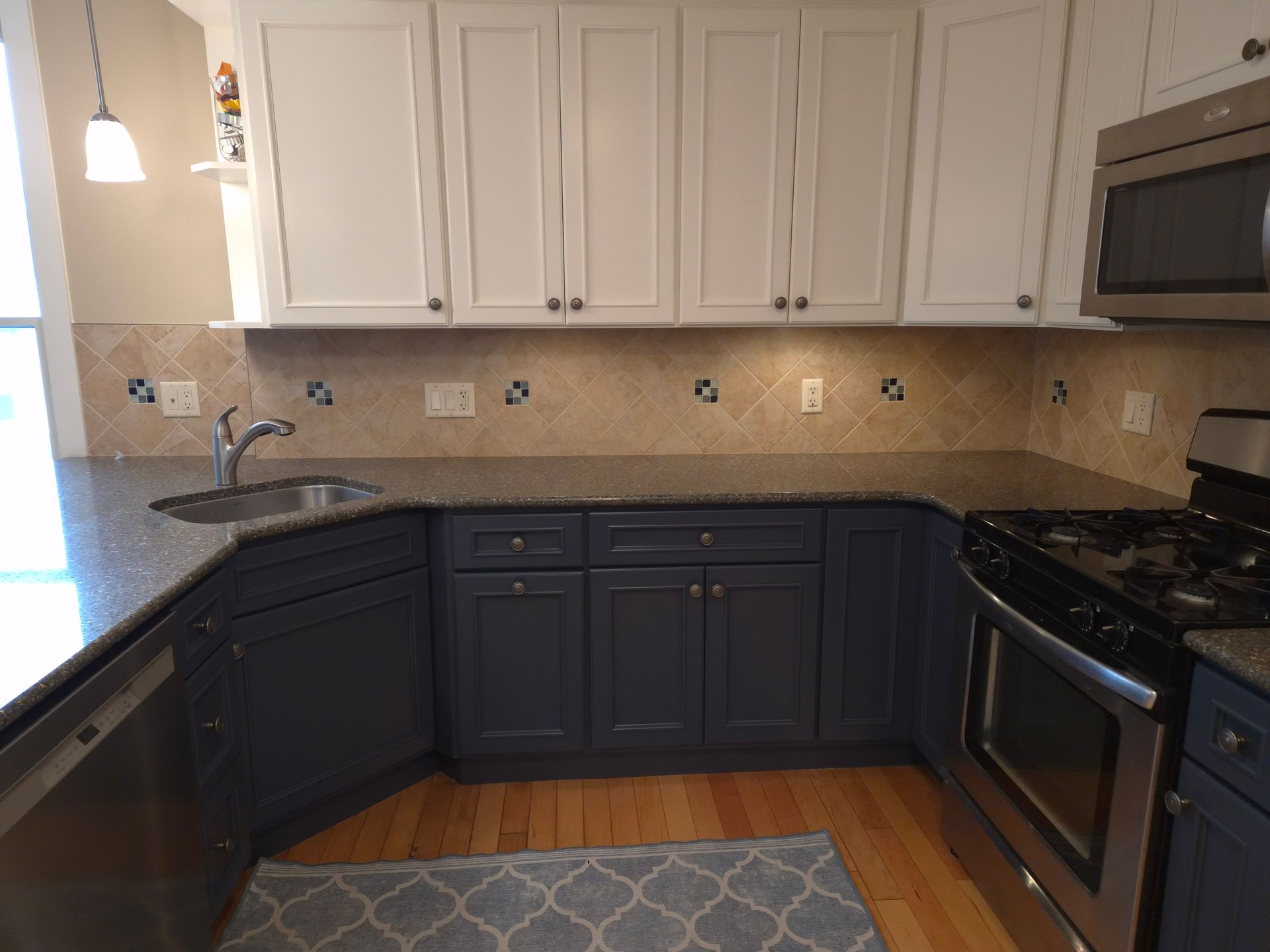 Kitchen with white upper cabinets, dark blue lower cabinets, and stainless steel appliances.