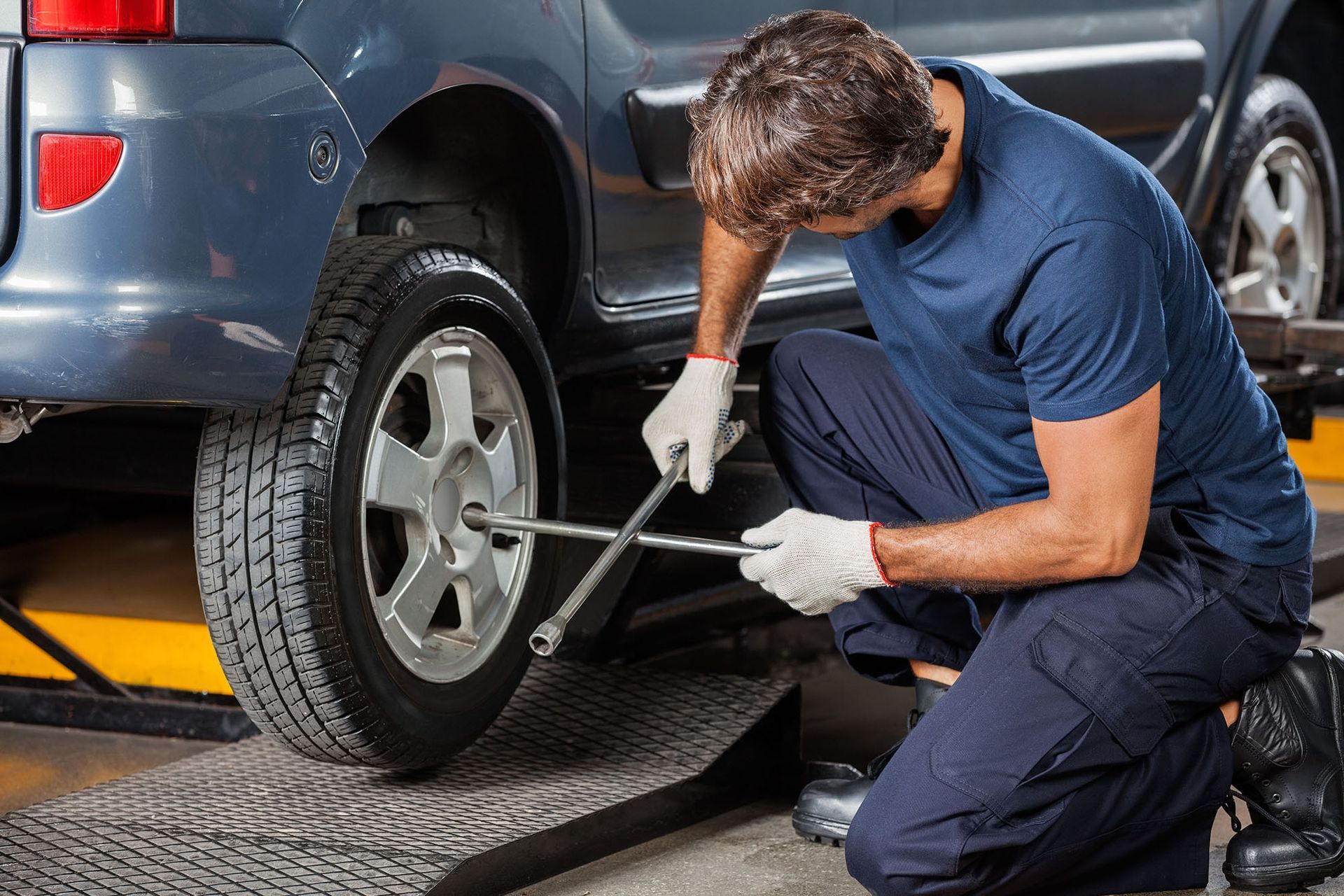 A man is changing a tire on a car with a wrench