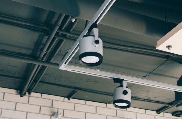 Two white hanging ceiling lights against an exposed industrial ceiling and brick wall