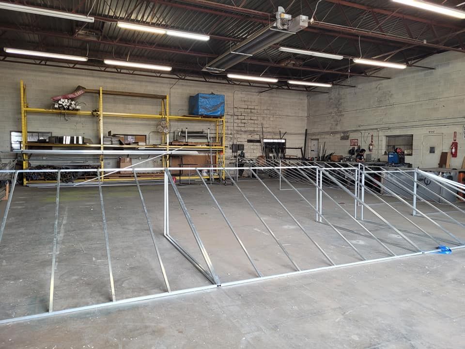 Metal framework inside a workshop with shelving and a person working in the background.