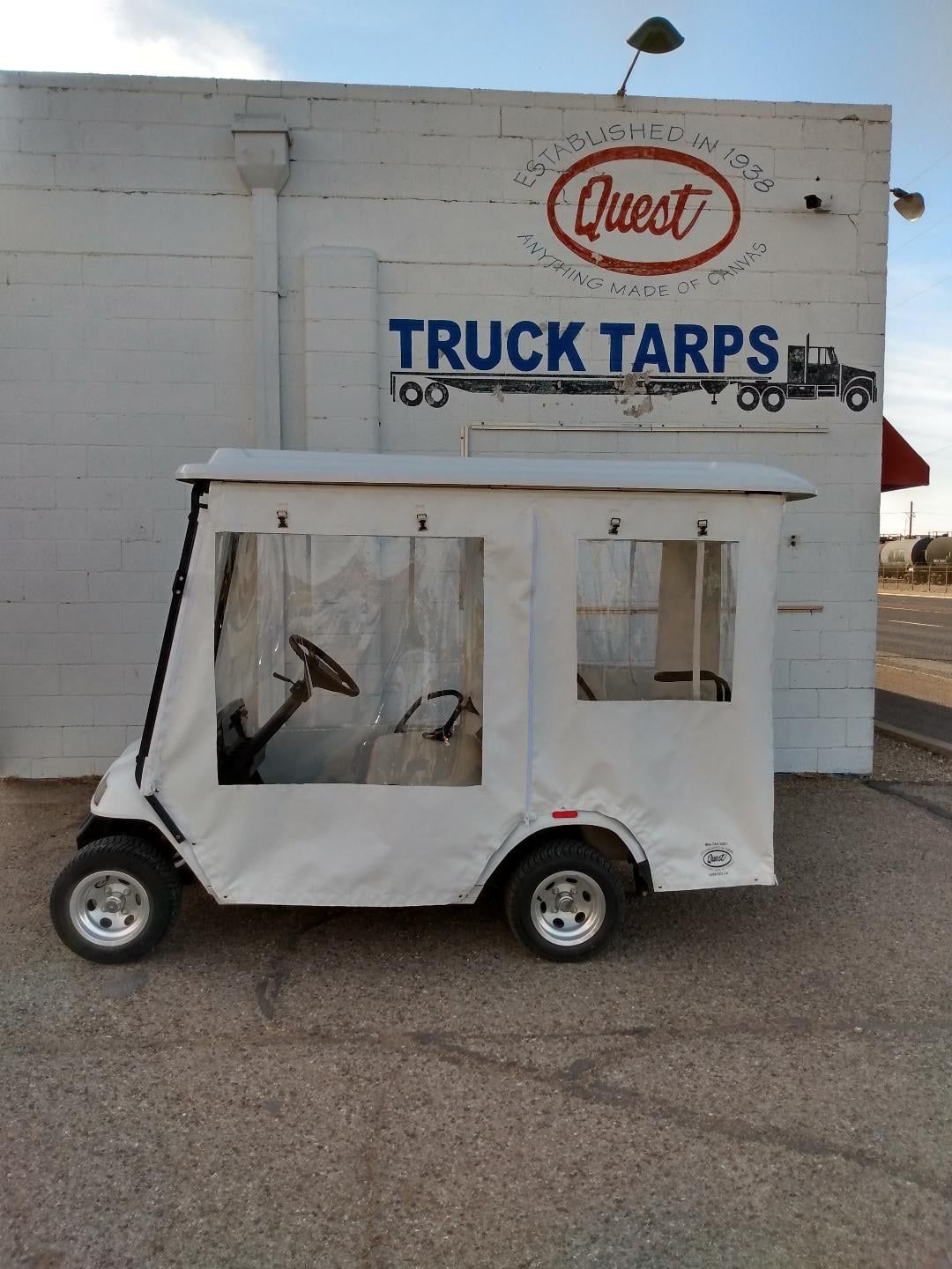 White golf cart with enclosed cab in front of a building with a 