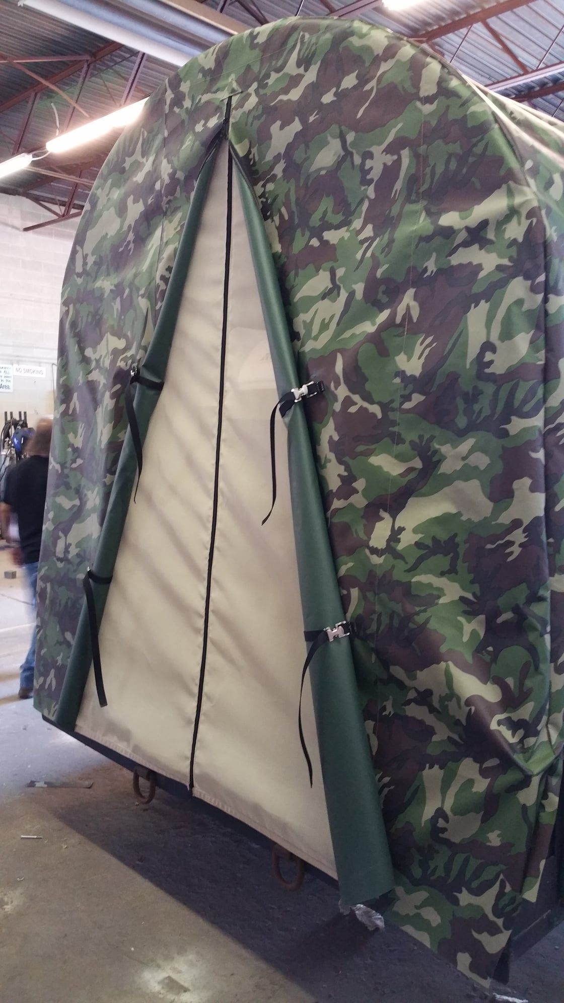 Camouflage fabric enclosure with tan doorway and dark green trim.