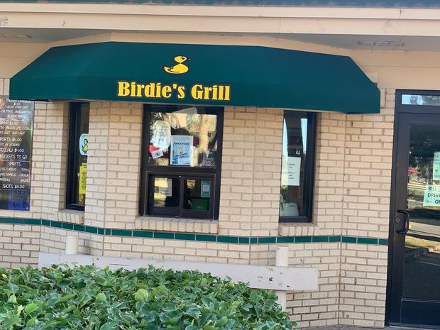 Birdie's Grill storefront with green awning, yellow text, and a duck logo. Beige brick exterior.