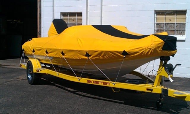 Yellow boat covered with a yellow and black tarp on a yellow trailer.