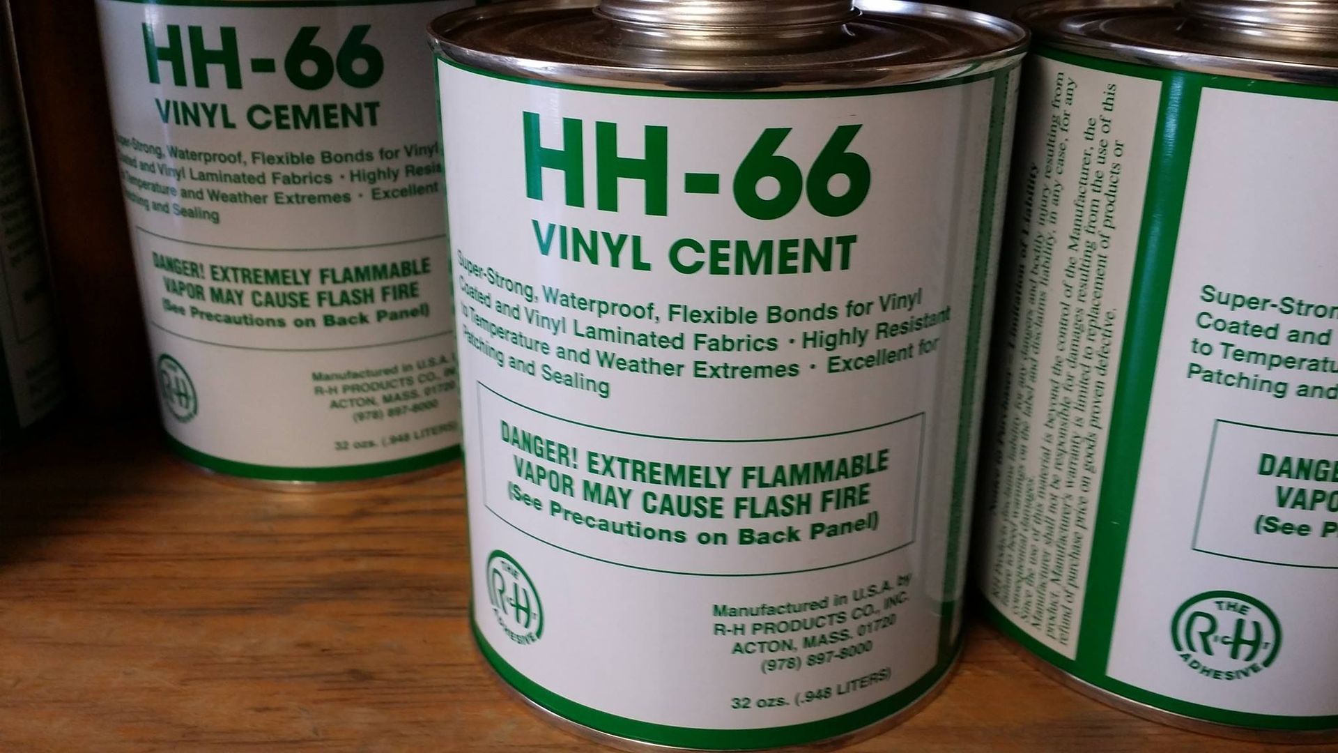 Three cylindrical cans of HH-66 Vinyl Cement, with green and white labels, warning of flammability.