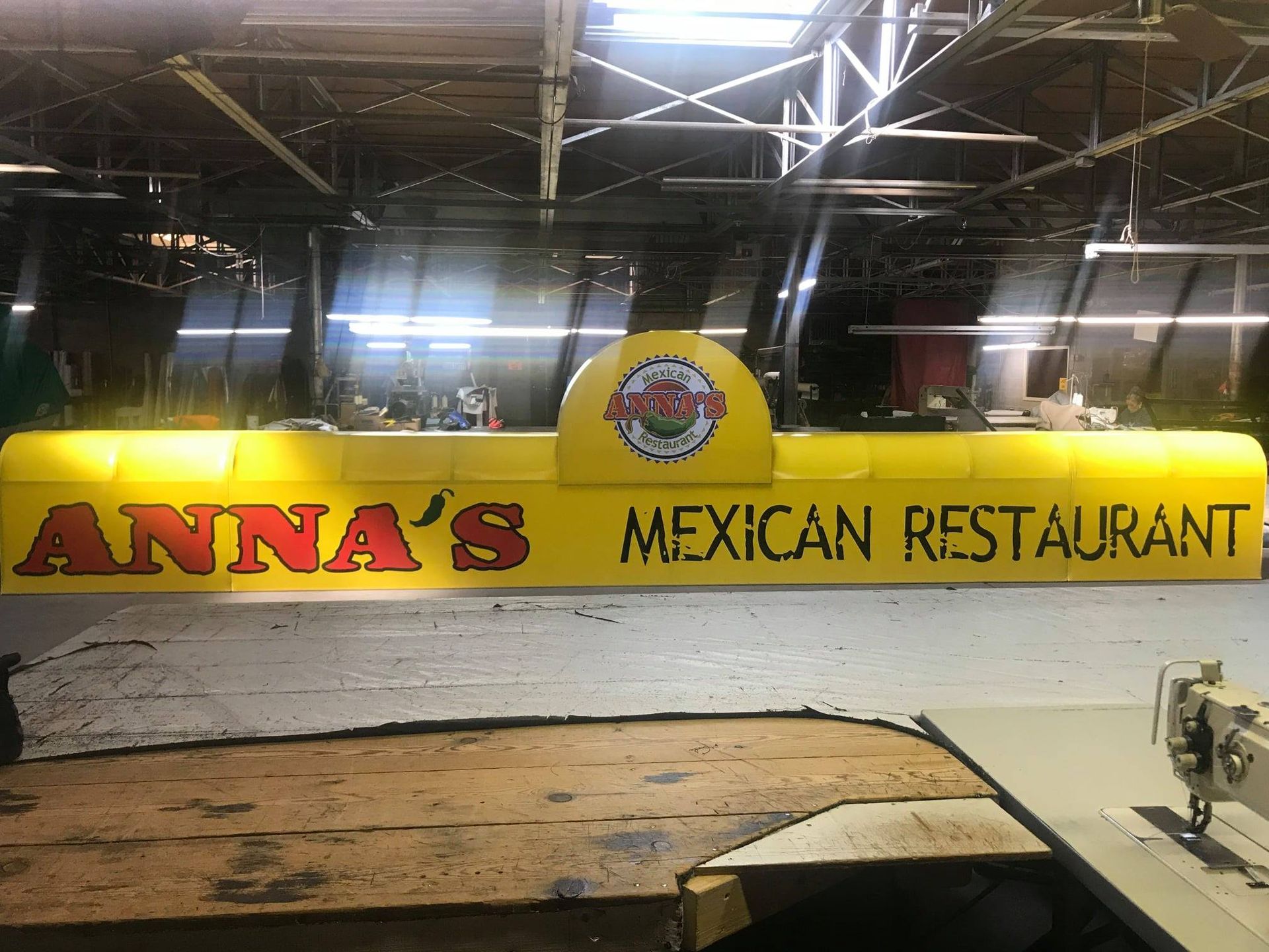 Yellow sign for Anna's Mexican Restaurant. Red text on yellow background. Logo in a half dome.