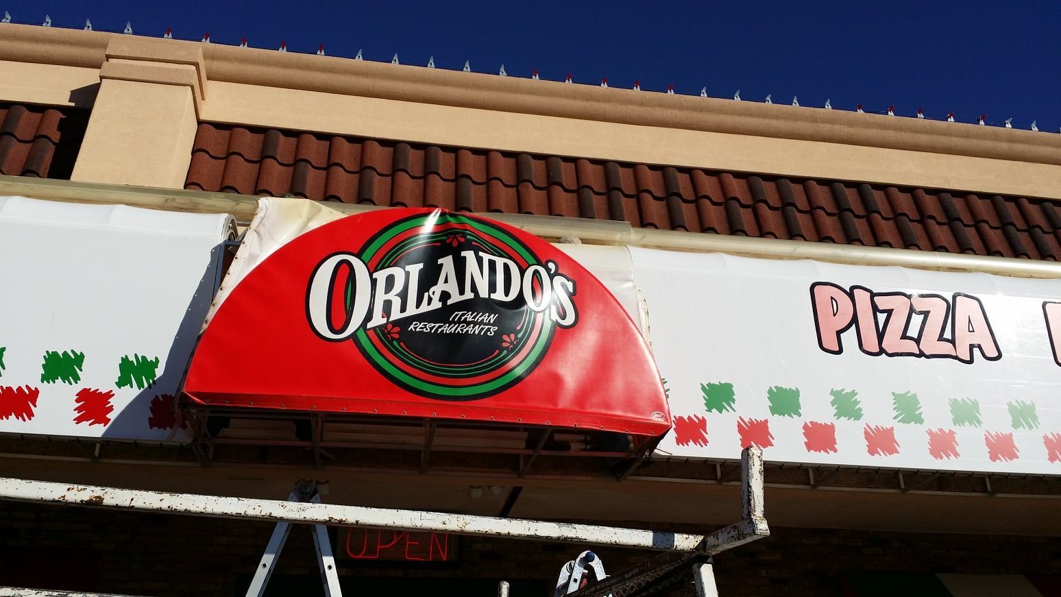 Orlando's Pizza restaurant sign with a red awning. The sign has a red and green design on a white background.