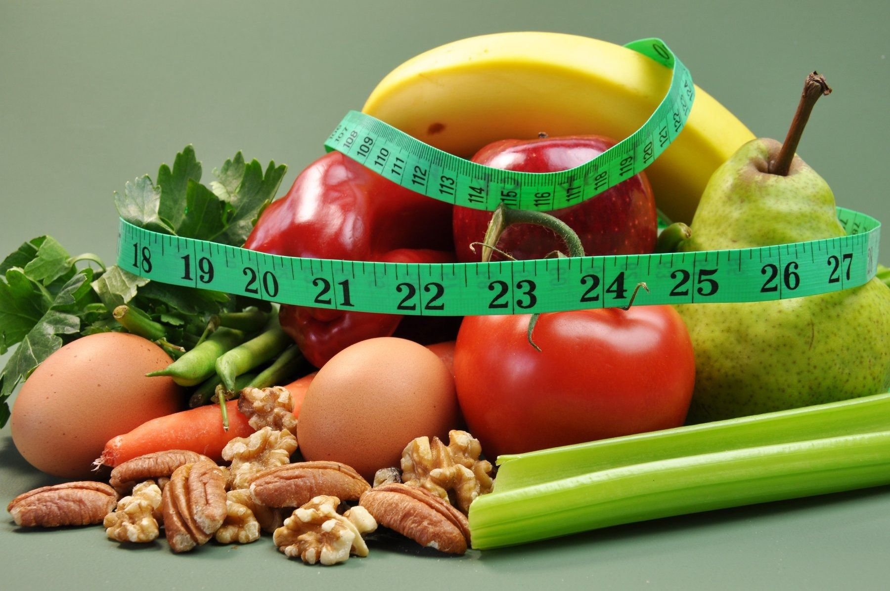 Fruits, vegetables, nuts, and eggs with a measuring tape. Healthy eating concept.