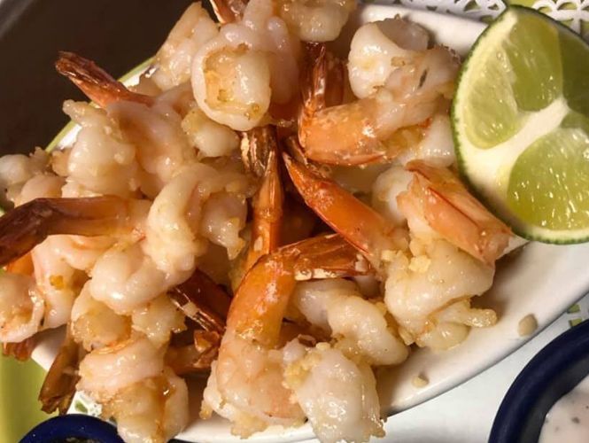 Garlic butter shrimp in a white bowl with lime wedge