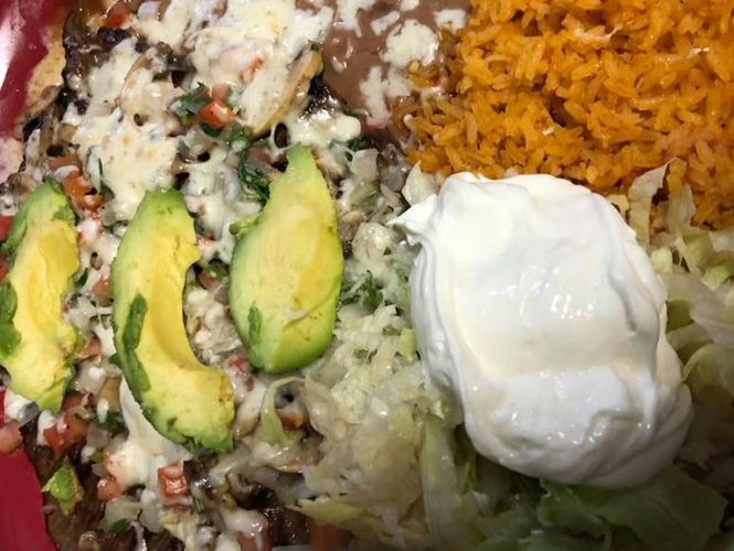 Mexican food platter with avocado slices, rice, sour cream, and shredded lettuce