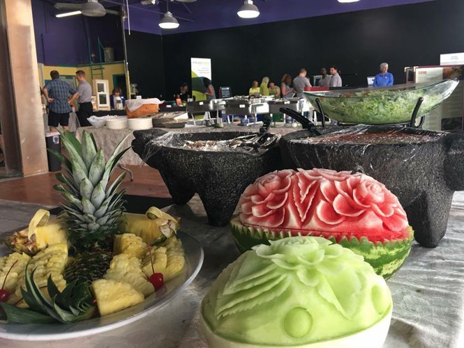 Buffet with fruit carving, salsas in stone bowls, people in background
