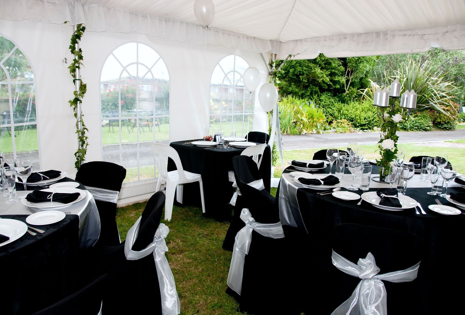 White tent with tables set for a black and white event outdoors.