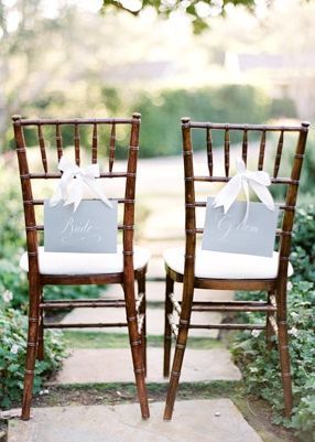Two wooden chairs with white cushions and signs that say