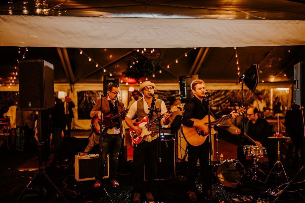 Band performing live on stage at night with string lights.