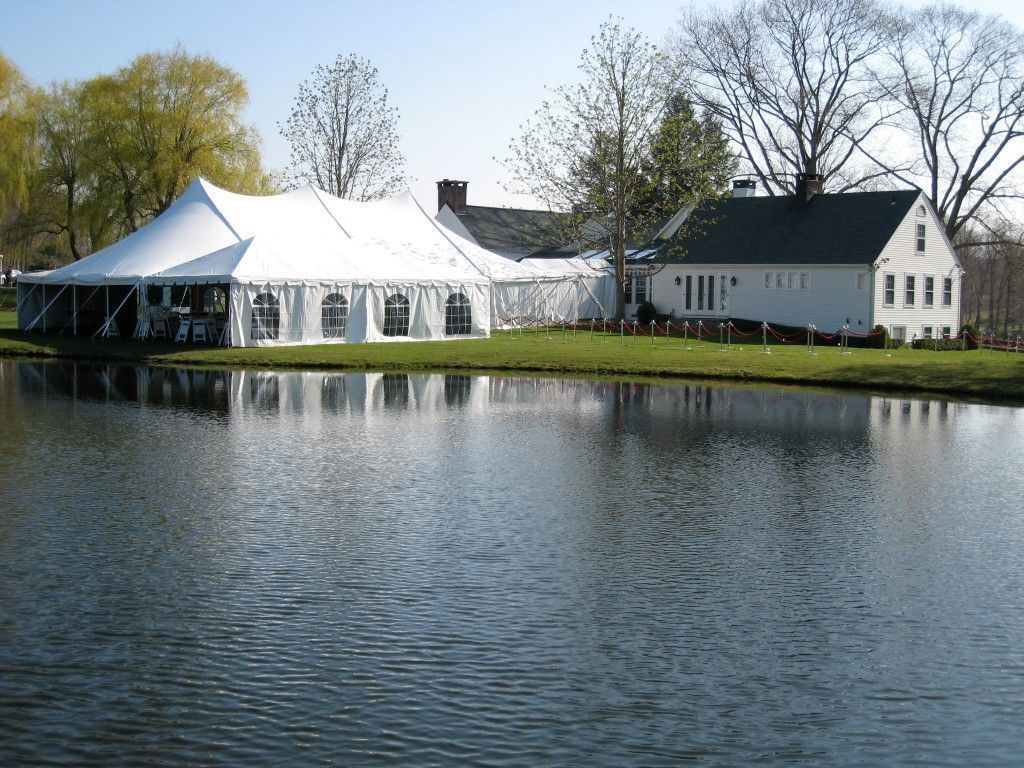 White tent next to white building on the edge of a pond, under a sunny sky.