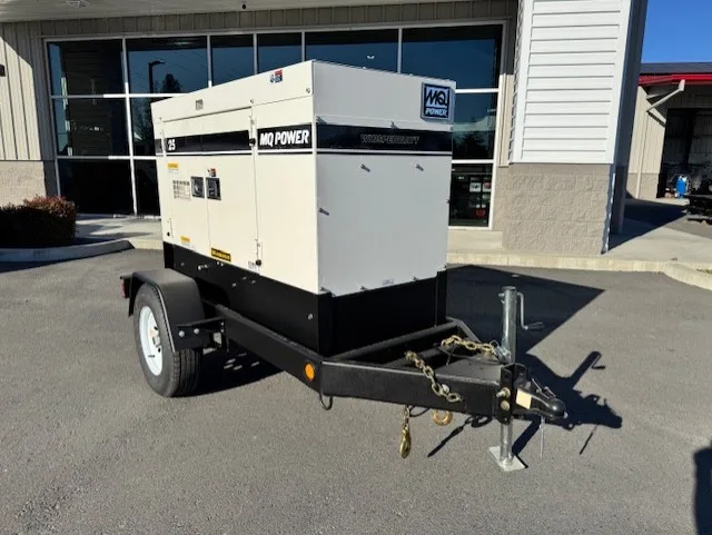 A beige and black generator on a trailer parked outside a building.