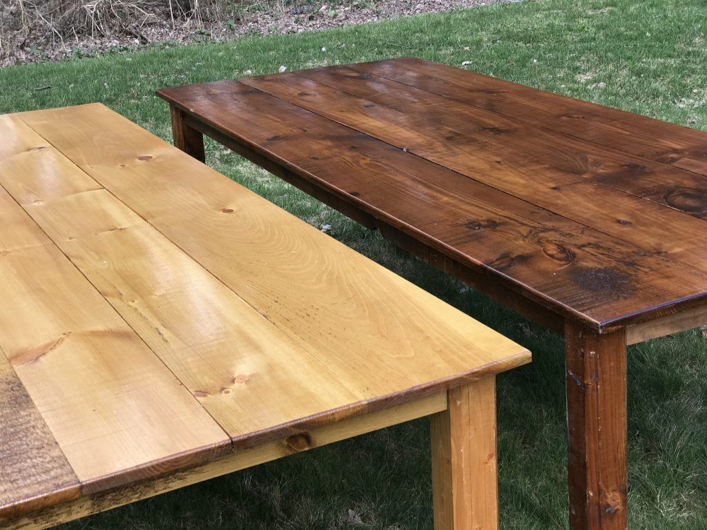 Two wooden tables, one light and one dark, on green grass.