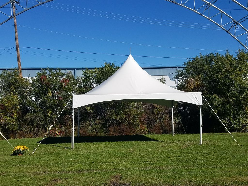 White tent on green grass, blue sky background.