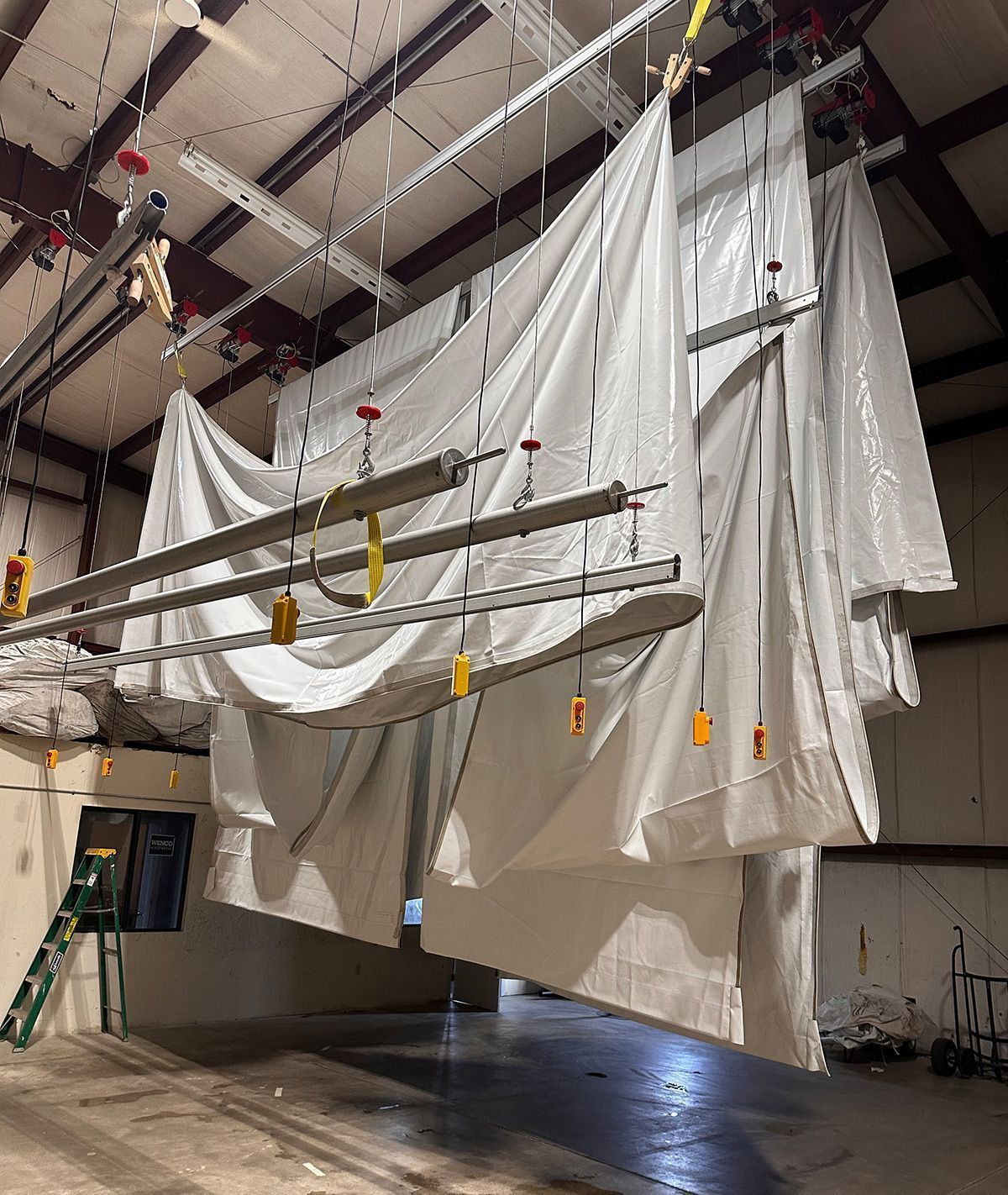 White fabric sheets hanging from a ceiling-mounted track system in a warehouse.