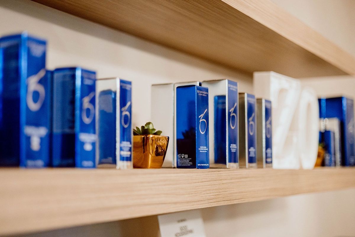 Blue and white product boxes lined on a wooden shelf, a small plant in a gold pot in the center.