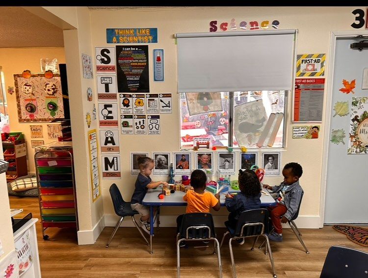 Children sitting and playing in a colorful preschool classroom with learning posters on the walls