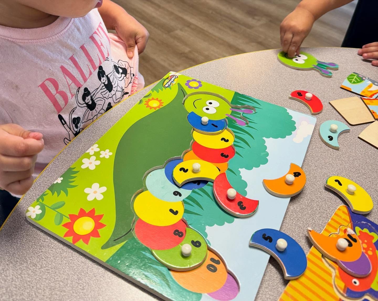 Children playing with a colorful caterpillar puzzle on a table.