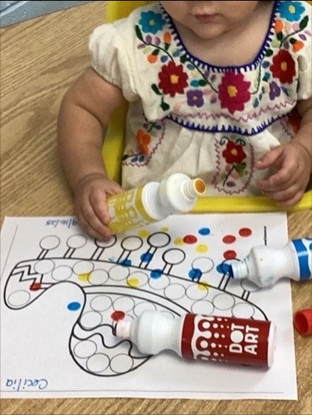 Child using dot art markers on a guitar-shaped coloring sheet.