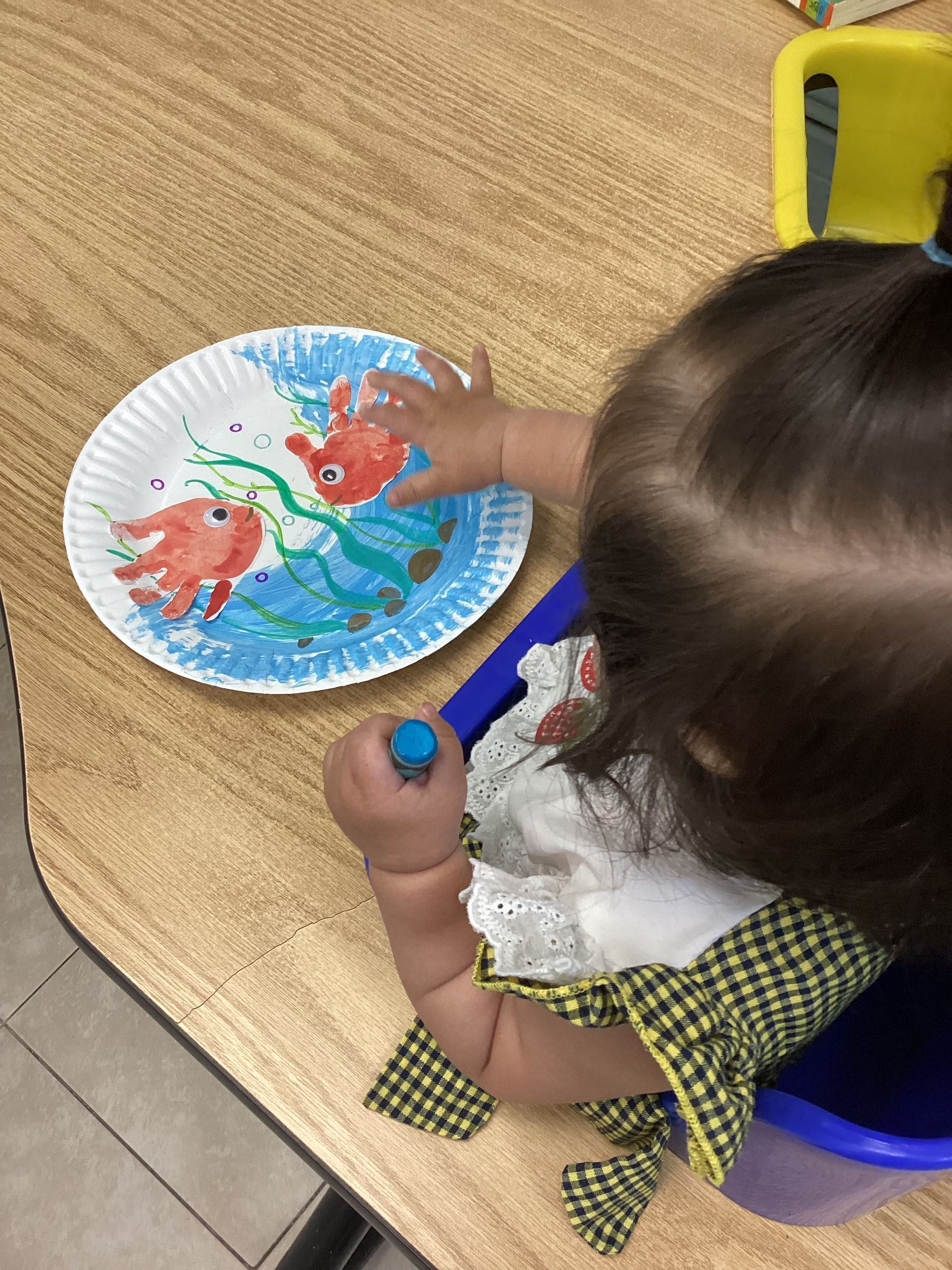Child painting on a paper plate with red and blue paint.