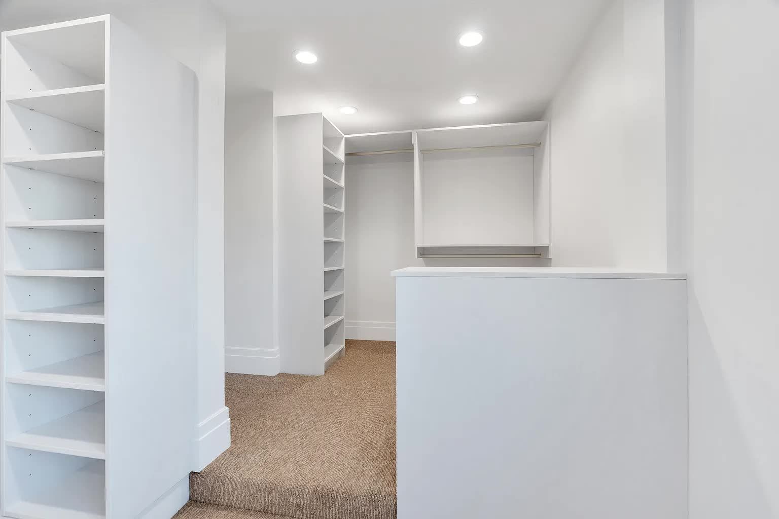 Empty white walk-in closet with carpeted floor, shelves, and recessed lighting.