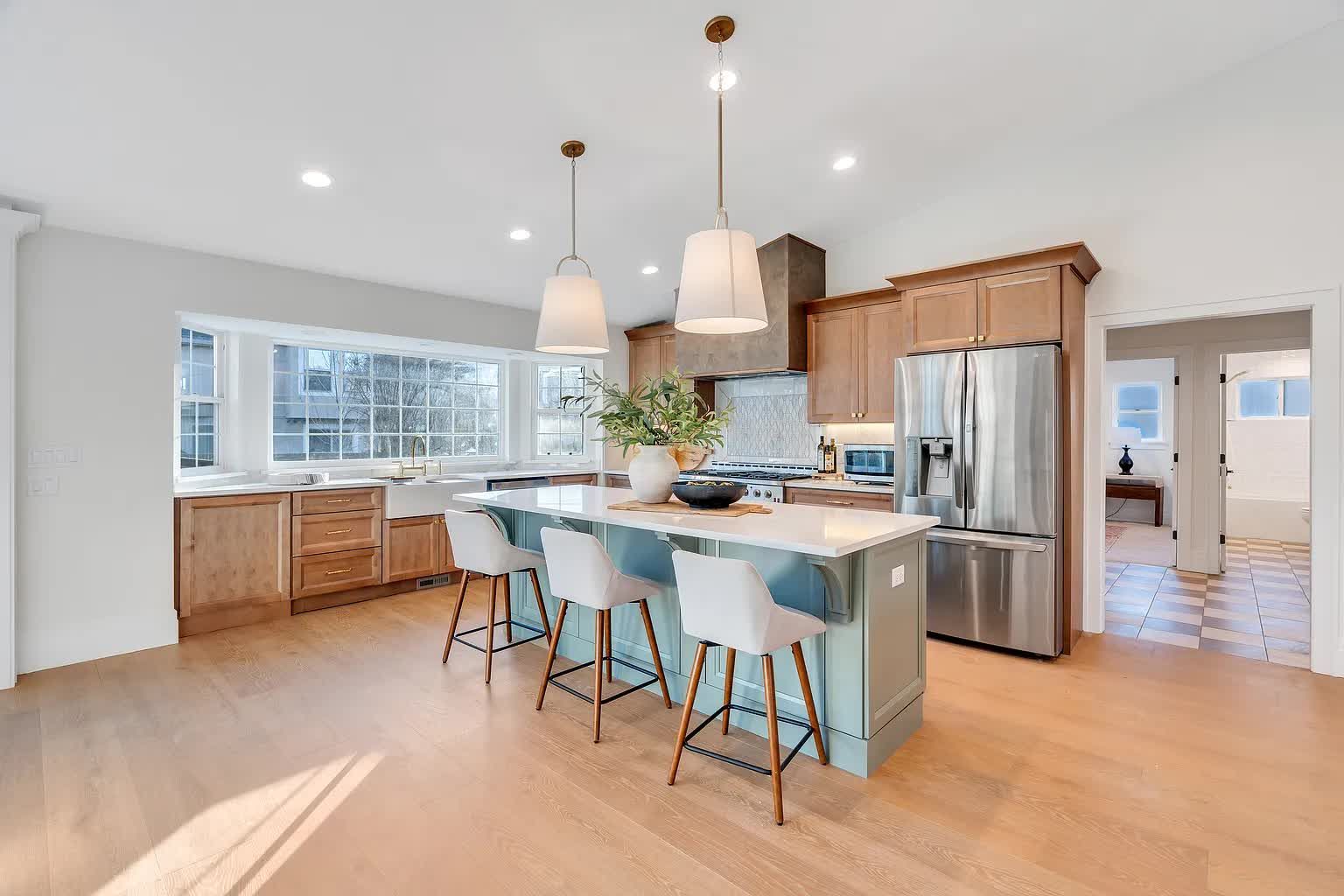 Kitchen with light wood cabinets, blue island, and stainless steel appliances.