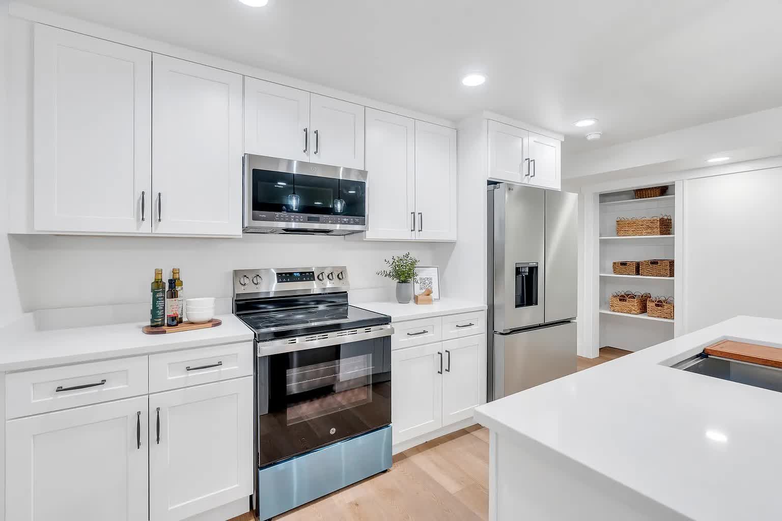 White kitchen with cabinets, stainless steel appliances, and pantry.