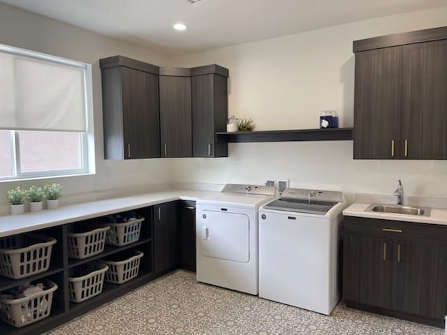 Laundry room with dark cabinets, white countertops, washer, dryer, sink, and baskets.