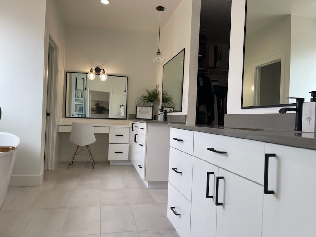 Spacious modern bathroom with white cabinets, gray countertops, and large mirrors.