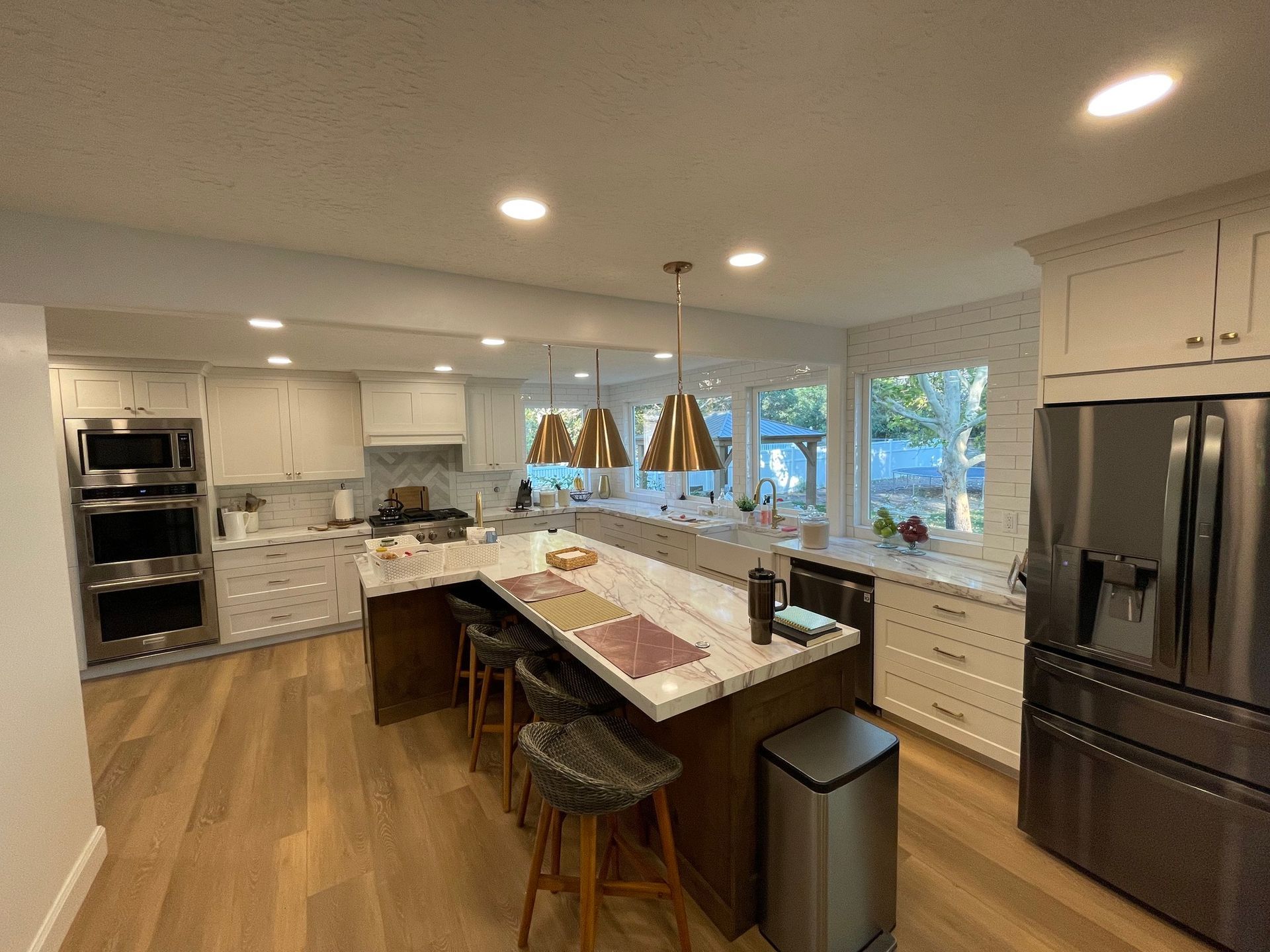 A modern kitchen with a large island, stainless steel appliances, and wood flooring.