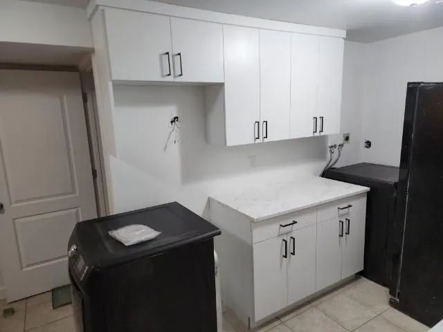 White kitchen cabinets with black hardware and a marble countertop.
