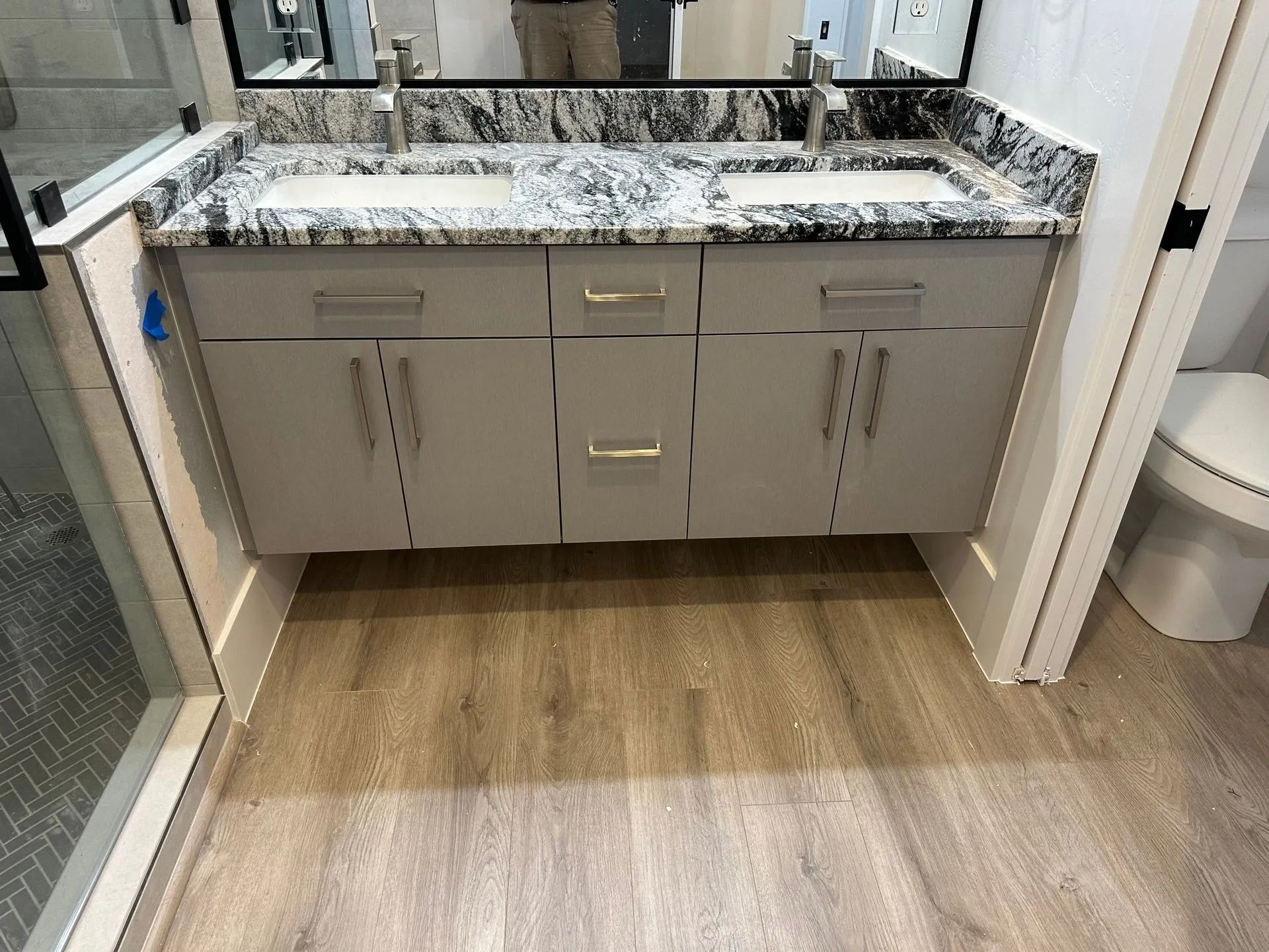 Bathroom with gray floating vanity, marble countertop, and wood-look flooring.